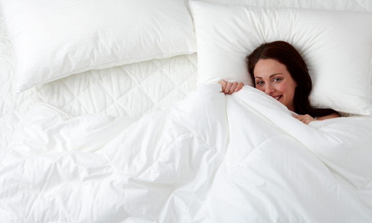A duvet cover and a smiling woman in bed.